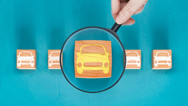 Wooden block with a car painted on it under a magnifying glass